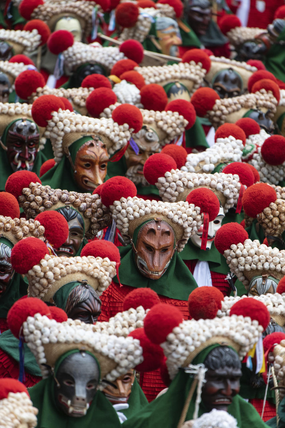 Hundreds of fools of the Elzacher Schuttig walk through the main street during the traditional Schuttig jump carnival parade in Elzach, Germany, Sunday, Feb 23, 2020. (Patrick Seeger/dpa via AP)