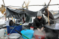 A woman washes dishes in the Oceti Sakowin camp in a snow storm during a protest against plans to pass the Dakota Access pipeline near the Standing Rock Indian Reservation, near Cannon Ball, North Dakota, U.S. November 28, 2016. REUTERS/Stephanie Keith