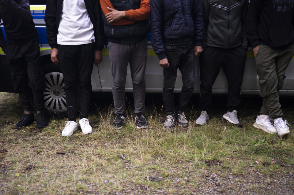 Migrants wait at a police car after they illegally crossed the border from Poland into Germany and tracked down from a Federal Police patrol in a forest near Forst southeast of Berlin, Germany, Wednesday, Oct. 11, 2023. (AP Photo/Markus Schreiber)