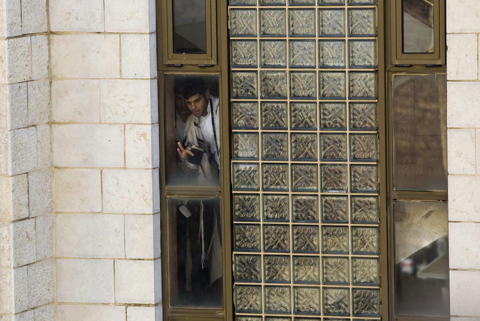 An ultra-orthodox Jew looks out a window near the scene of an attack at a Jerusalem synagogue