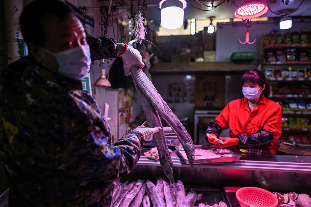 A man wearing a face mask holds a fish in a market in Wuhan, in China's central Hubei province on April 7, 2020. Wuhan, the central Chinese city where the coronavirus first emerged last year, partly reopened on March 28 after more than two months of near total isolation for its population of 11 million.