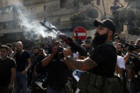 A supporter of the Shiite Amal group fires in the air during the funeral processions of Hassan Jamil Nehmeh, who was killed during Thursday clashes, in the southern Beirut suburb of Dahiyeh, Lebanon, Friday, Oct. 15, 2021. Dozens of gunmen opened fire in the air Friday south of Beirut during the funeral of persons killed in hours of gun battles between heavily armed gunmen the day before that left several people dead and terrorized the residents of Beirut. (AP Photo/Bilal Hussein)