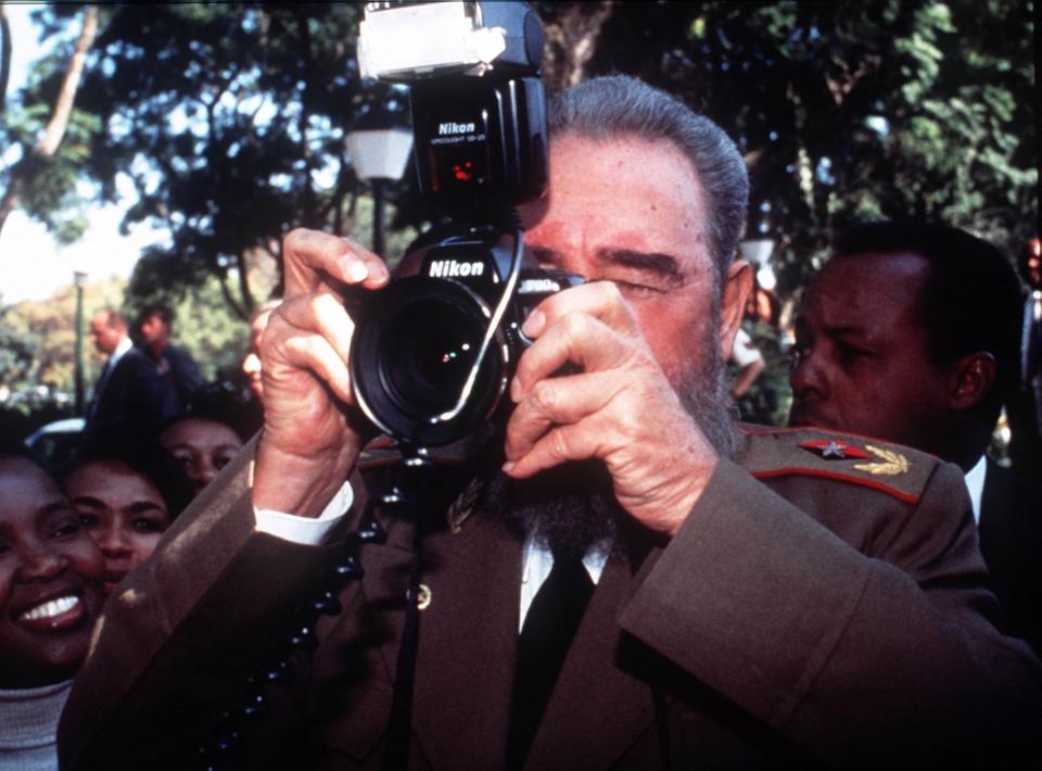 FILE - In this May 10, 1994 file photo, Cuban leader Fidel Castro briefly uses the camera of photojournalist Desmond Boylan outside the president's residence as he leaves for the inauguration ceremony for South Africa's first black President Nelson Mandela, in Pretoria, South Africa. (AP Photo/Gary Bernard, FILE)