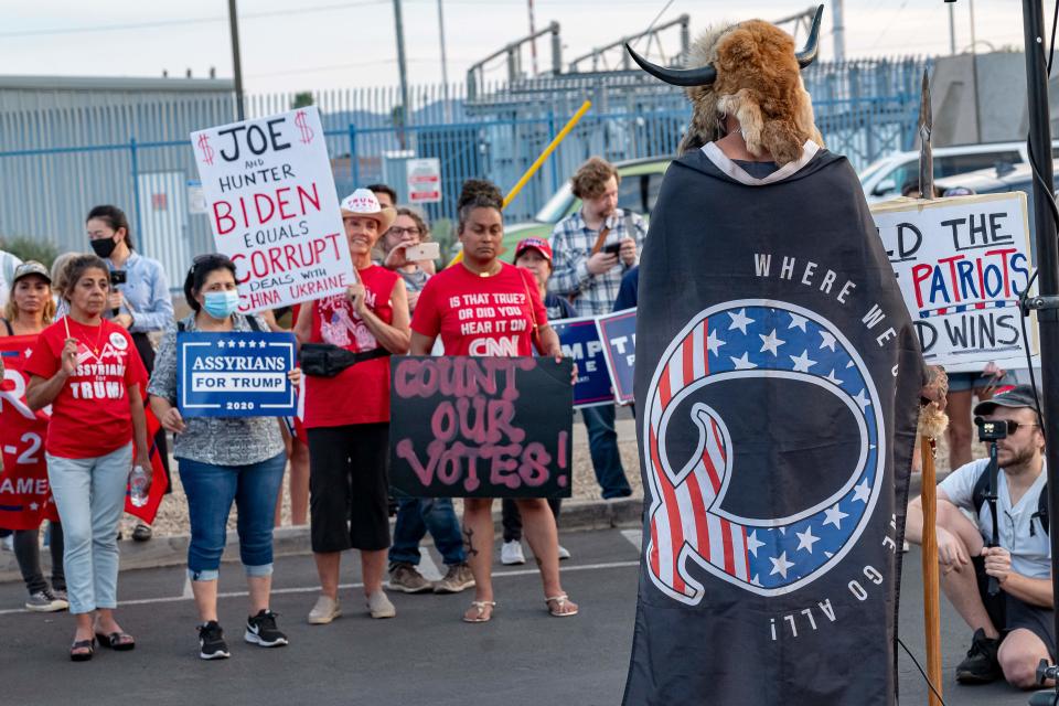 Jake A, 33, aka Yellowstone Wolf, from Phoenix, wrapped in a QAnon flag, addresses supporters of US President Donald Trump as they protest outside the Maricopa County Election Department as counting continues after the US presidential election in Phoenix, Arizona, on November 5, 2020. (Olivier Touron/AFP via Getty Images)