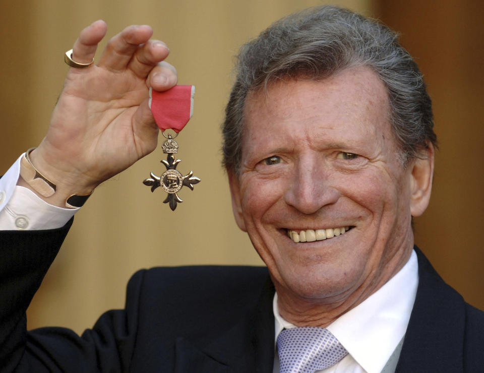 Johnny Briggs poses for the media after collecting an MBE from Queen Elizabeth II at Buckingham Palace in London. British actor Johnny Briggs, best known for his role as businessman Mike Baldwin in the long-running TV soap opera “Coronation Street,” has died. He was 85. A statement from his family released Sunday, Feb. 28, 2021 said Briggs died peacefully after a long illness.