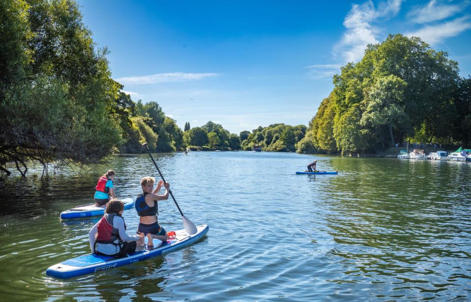  Young people paddleboard on the River Thames near Richmond, the happiest place to live in the UK.