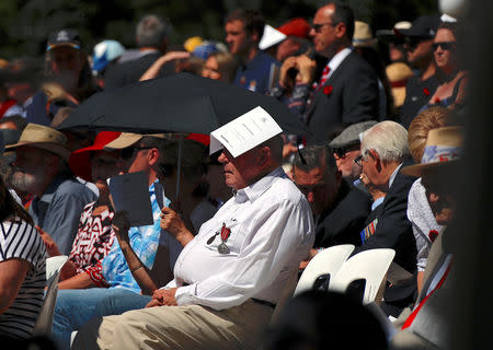 A veteran covers his head from the sun using an official program during a memorial service at the ANZAC Memorial to mark the centenary of the Armistice ending World War One, in Sydney, Australia, November 11, 2018. REUTERS/David Gray