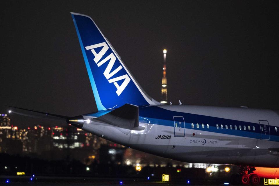 The tail of an ANA plane, illuminated at night
