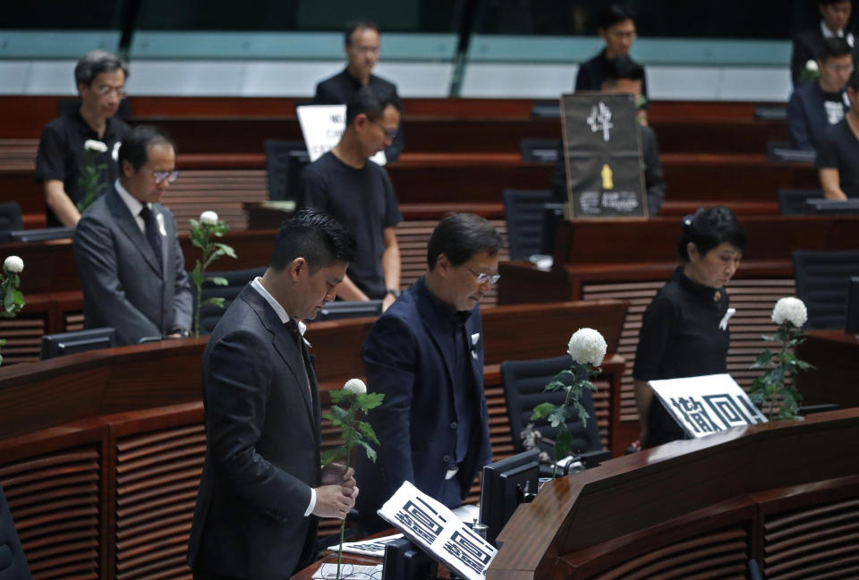 Pro-democracy lawmakers pay a silent tribute to the man who fell to his death on Saturday evening after hanging a protest banner on scaffolding on a shopping mall at the Legislative Council in Hong Kong, Wednesday, June 19, 2019. Hong Kong lawmakers are meeting for the first time in a week, after massive protests over an extradition bill that eventually was suspended. (AP Photo/Vincent Yu)