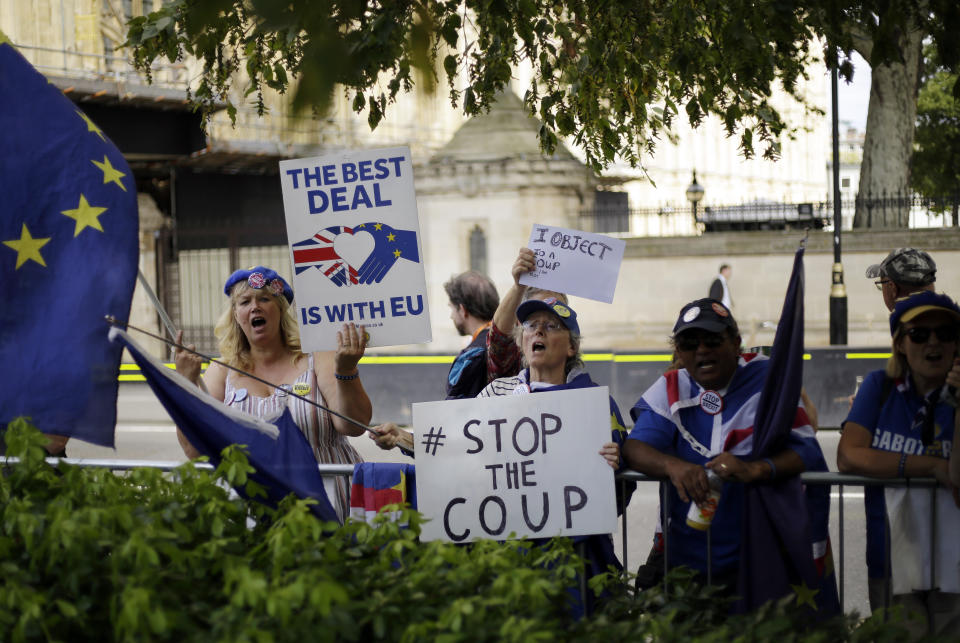 Anti-Brexit supporters wave flags and hold signs near the Houses of Parliament in central London, Wednesday, Aug. 28, 2019. British Prime Minister Boris Johnson asked Queen Elizabeth II on Wednesday to suspend Parliament, throwing down the gauntlet to his critics and causing outrage among opposition leaders who will have even less time to thwart a no-deal Brexit. (AP Photo/Matt Dunham)