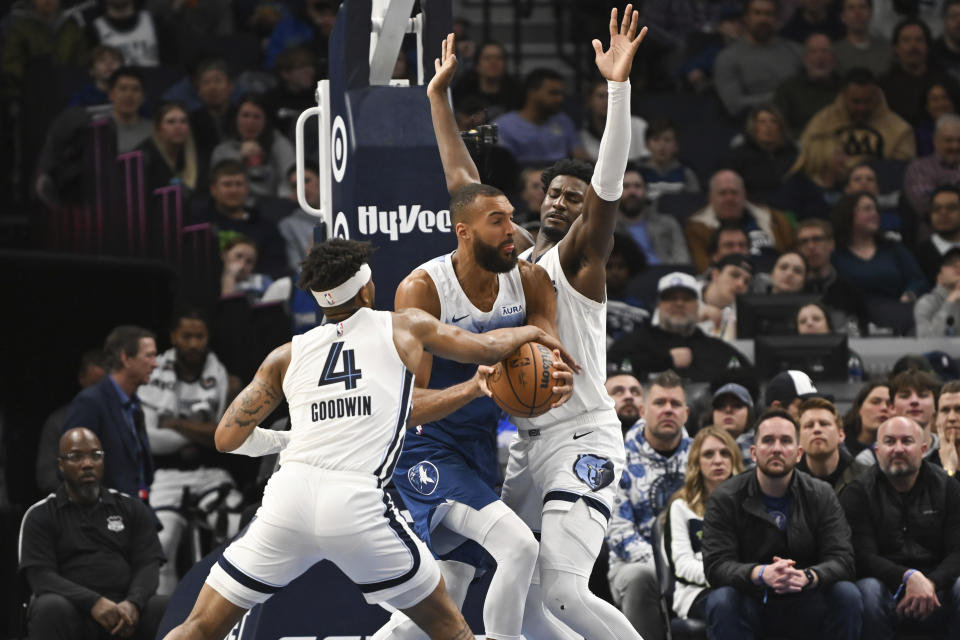 Minnesota Timberwolves center Rudy Gobert, center, is defended by Memphis Grizzlies guard Jordan Goodwin (4) and forward Jaren Jackson Jr. during the first half of an NBA basketball game Wednesday, Feb 28, 2024, in Minneapolis. (AP Photo/Craig Lassig)