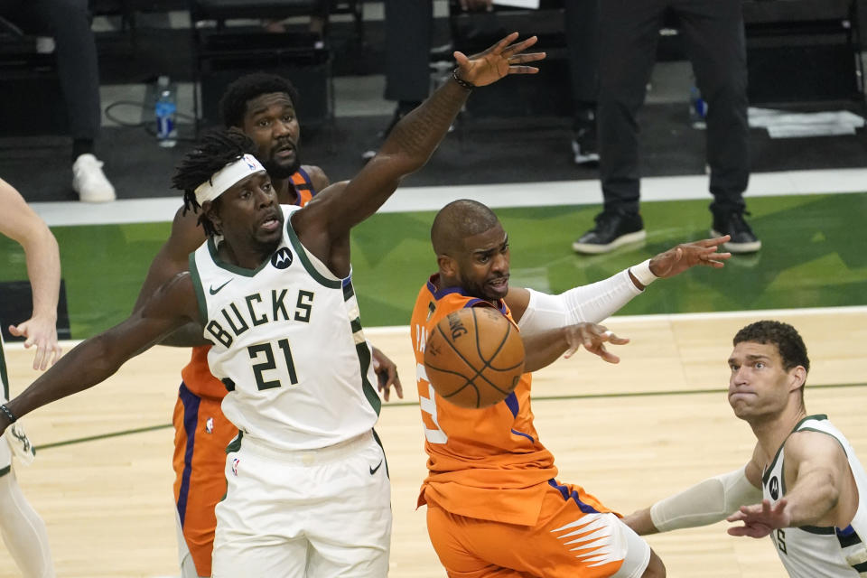 Phoenix Suns guard Chris Paul, center, fights for a rebound with Milwaukee Bucks guard Jrue Holiday (21) and center Brook Lopez, right, during the first half of Game 4 of basketball's NBA Finals in Milwaukee, Wednesday, July 14, 2021. (AP Photo/Paul Sancya)