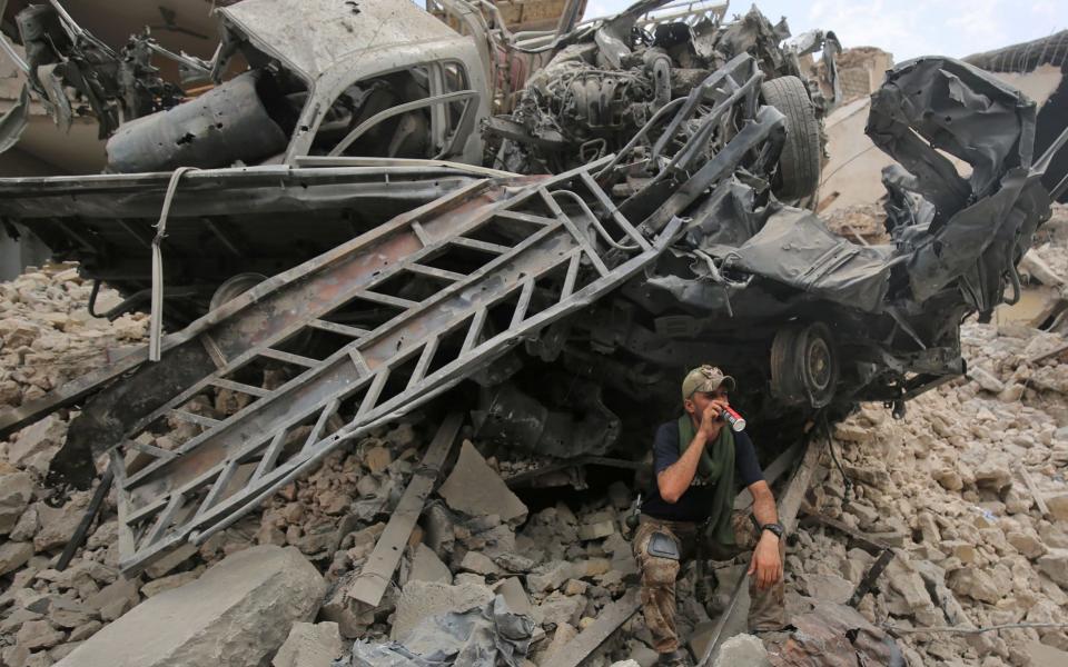 An Iraqi Counter-Terrorism Service (CTS) member drinks as he sits amid the rubble in the old city of Mosul  - Credit: AFP