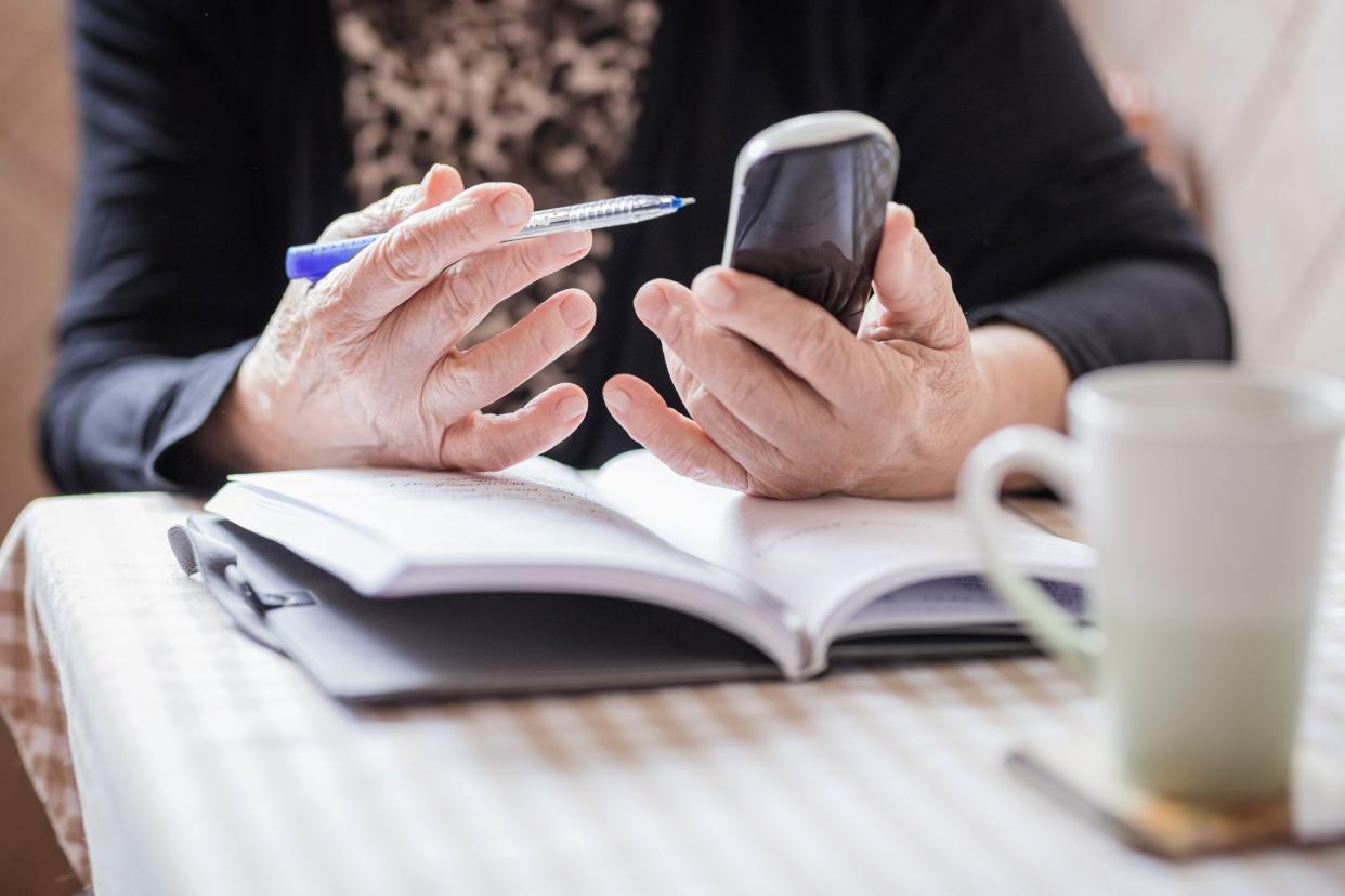 Woman with pen on her hand holding a phone