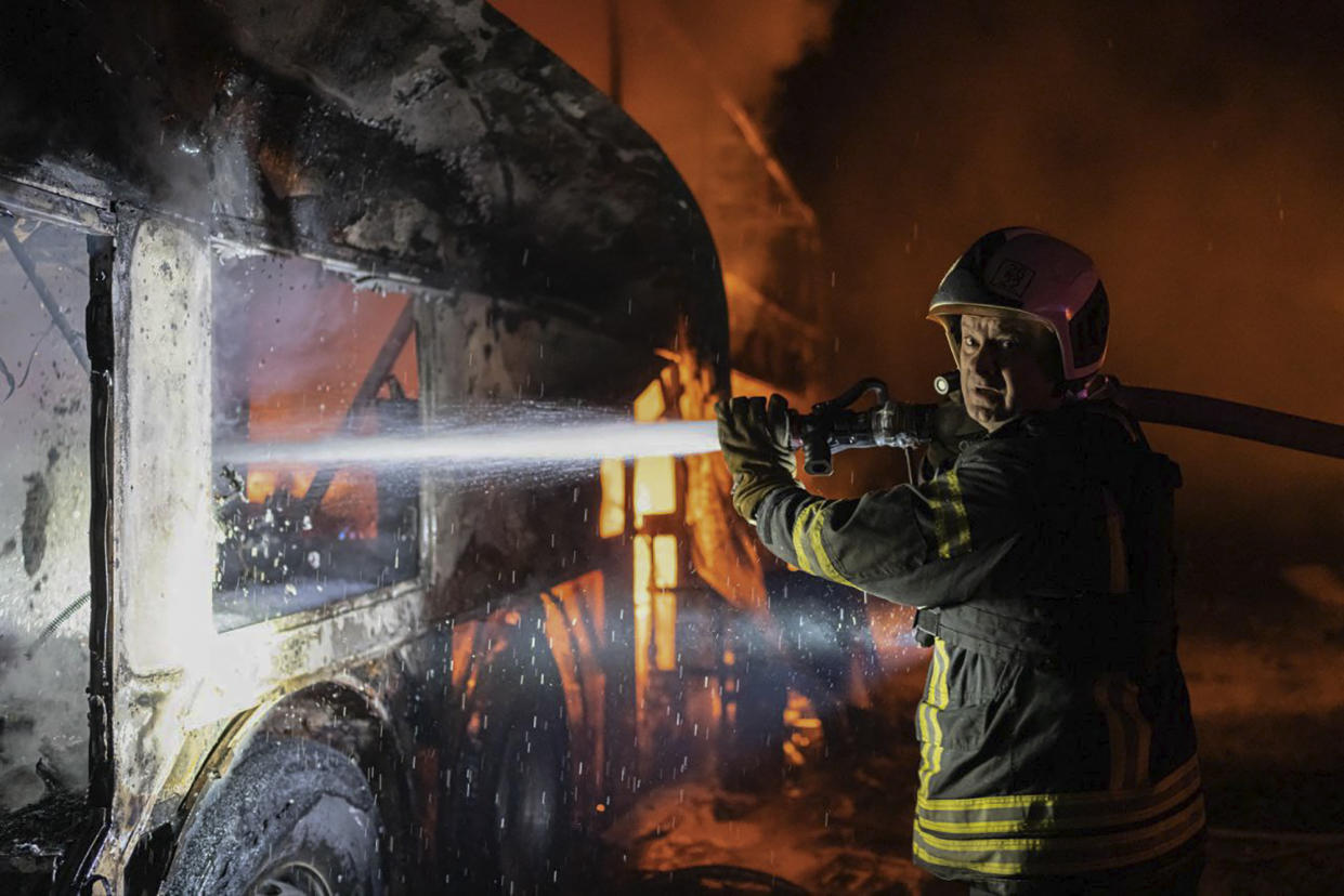 A firefighter tries to put out fire caused by fragments of a Russian rocket after it was shot down by air defense system during the night Russian rocket attack in Kyiv, Ukraine, early Tuesday, May 16, 2023. (Ukrainian Emergency Situations Ministry via AP)