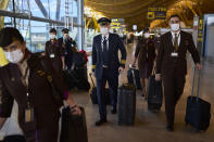 Flight crew members wearing face masks to prevent the spread of coronavirus walk along the Adolfo Suarez-Barajas international airport in Madrid, Spain, Thursday, Dec. 2, 2021. The coronavirus's omicron variant kept a jittery world off-kilter as reports of infections linked to the mutant strain cropped up in more parts of the globe. (AP Photo/Manu Fernandez)