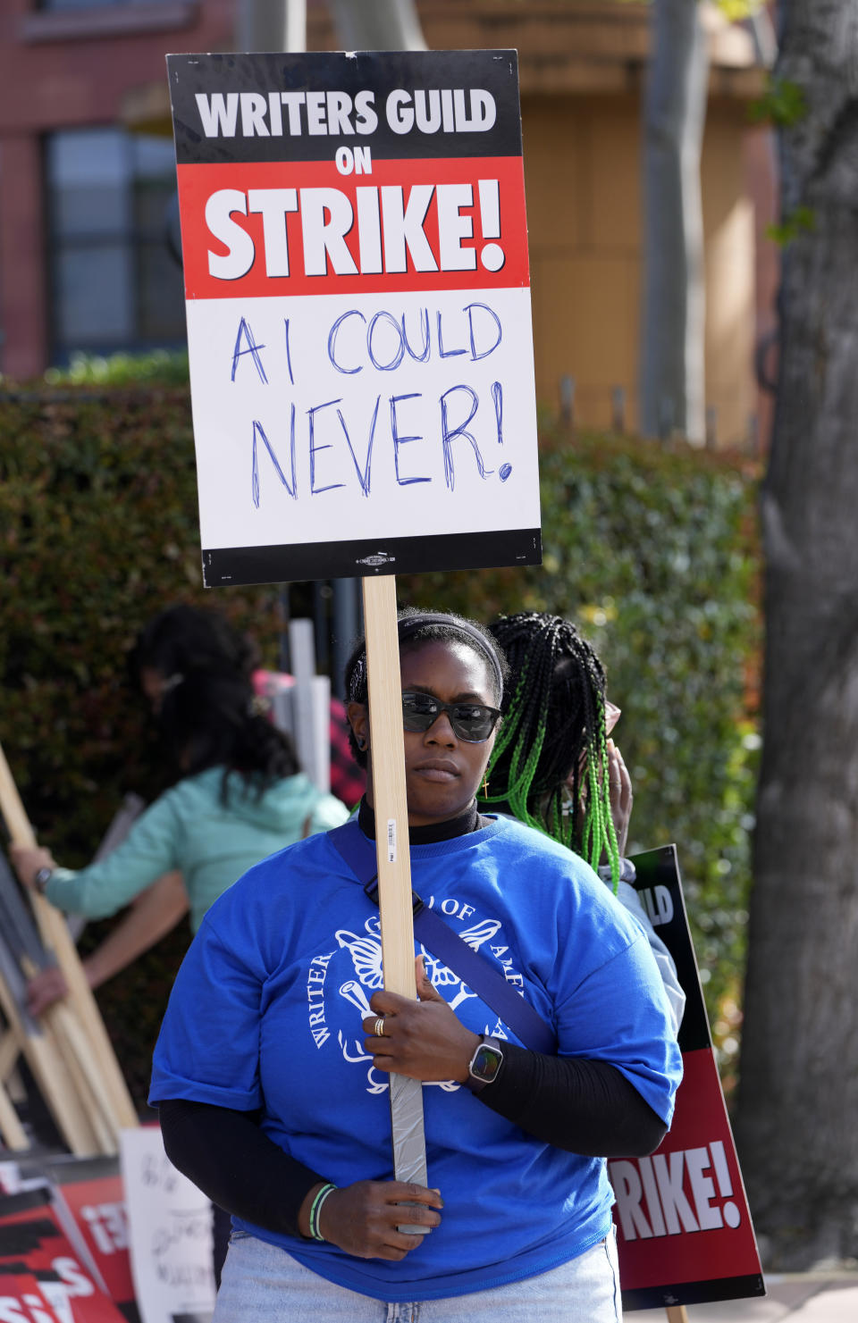 Chikodili Agwuna, guionista de la serie de televisión "Criminal Minds", sostiene un cartel en una manifestación del Sindicato de Guionistas de Estados Unidos frente a Walt Disney Studios, el martes 2 de mayo de 2023, en Burbank, California. Una de las peticiones de los guionistas es revisar el uso de Inteligencia Artificial (IA) en la escritura de guiones. (Foto AP/Chris Pizzello)