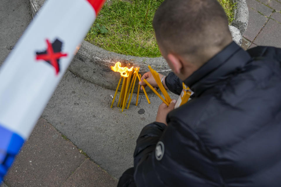 A man lights candles for victims near the Vladislav Ribnikar school in Belgrade, Serbia, Wednesday, May 3, 2023. A 13-year-old who opened fire Wednesday at his school in Serbia's capital drew sketches of classrooms and wrote a list of people he intended to target in a meticulously planned attack, police said. (AP Photo/Darko Vojinovic)