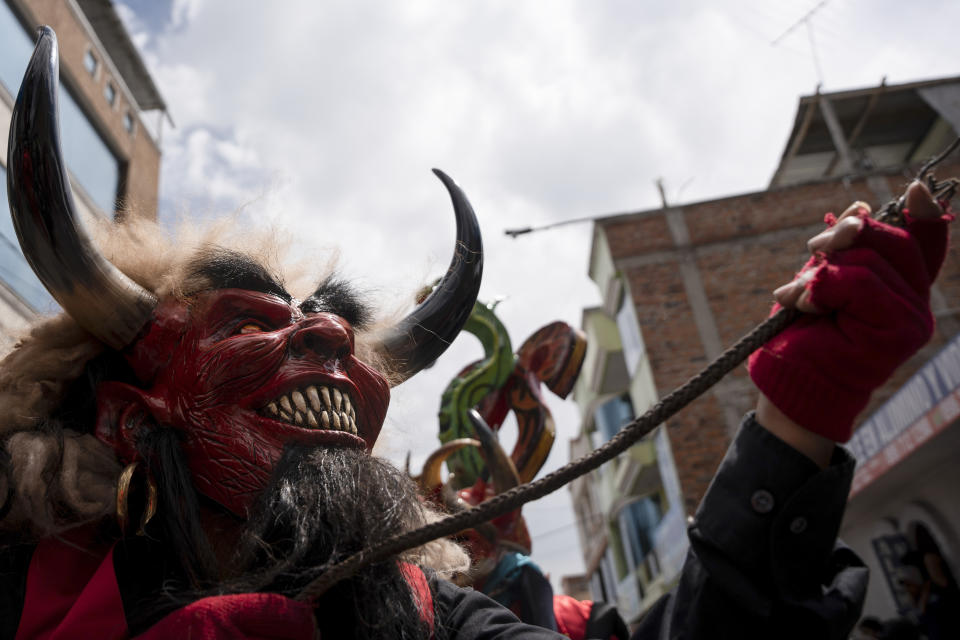 Wearing a devil mask, a reveler dances through the streets during the "Diablada de Pillaro," or the Devils of Pillaro festival, to send out the old year and bring in the new, in the Andean town of Pillaro, Ecuador, Jan. 1, 2024. (AP Photo/Carlos Noriega)