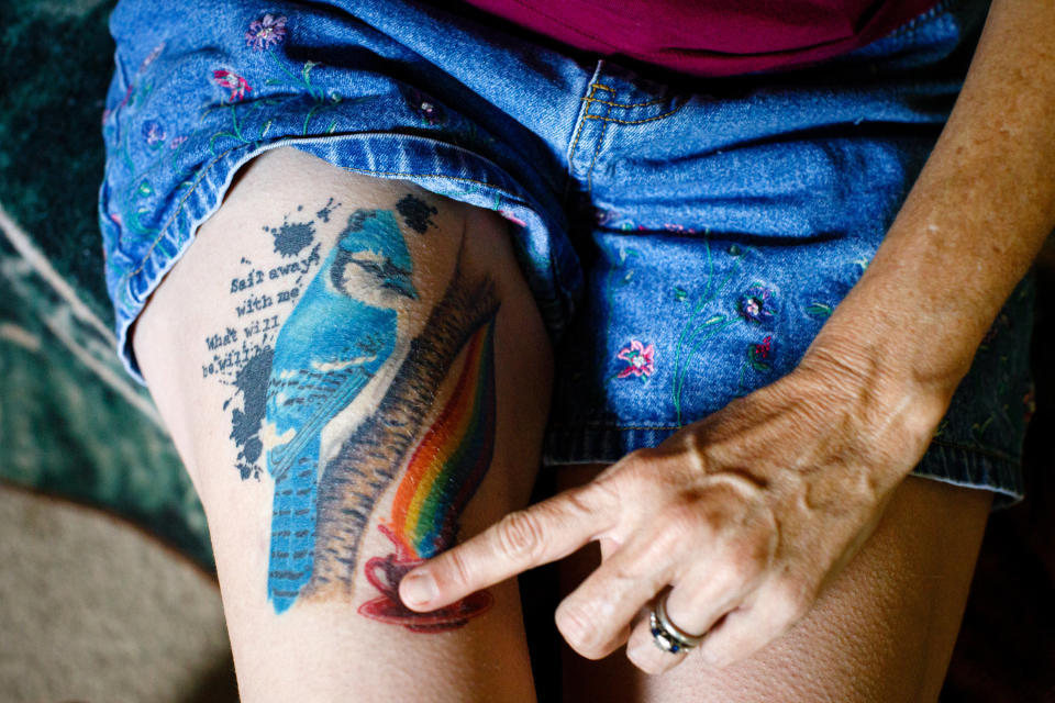 Meredith Lawrence shows the tattoo she got after her husband's death. The bluejay represents her husband, Jay; a cup of coffee is the way she loves to start her day; and the quote is "Sail away with me, what will be will be." (Photo: Dustin Chambers for HuffPost)