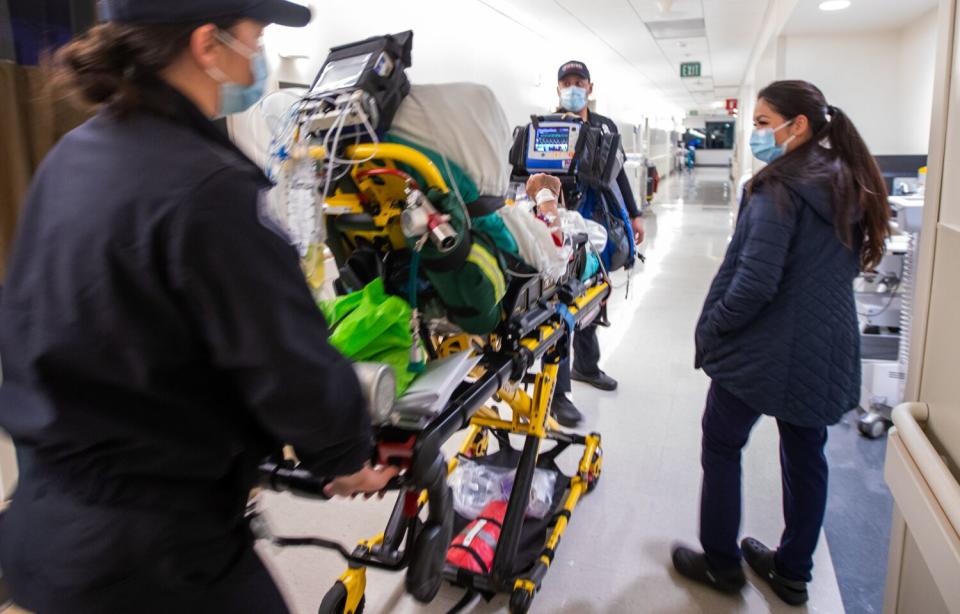 A medical worker pushing a gurney through a hallway