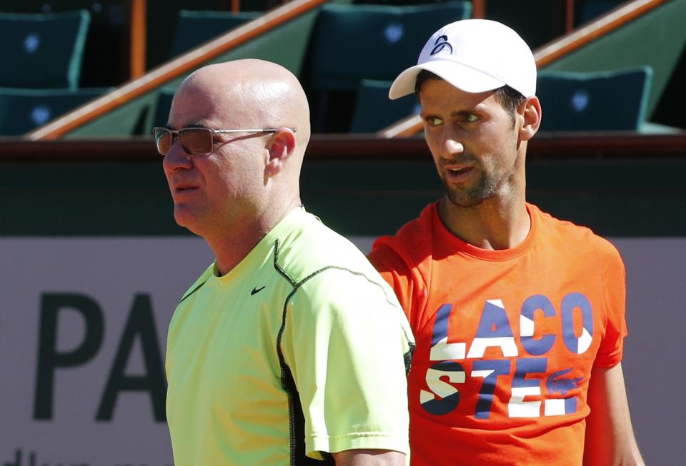 Serbia's Novak Djokovic watches Andre Agassi, left, of the U.S, during a training session for the French Open tennis tournament at the Roland Garros stadium