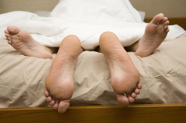 View of feet of couple having sex in bed.