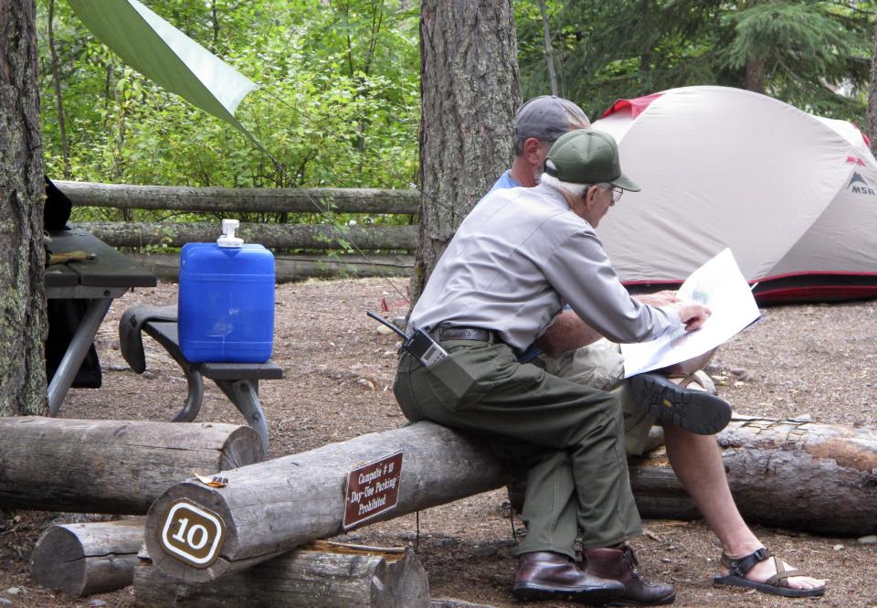 This Sept. 5, 2013 photo shows Lyle Ruterbories pointing out routes on a map with a visitor to the Kintla Lake Campground in Glacier National Park, Mont. Ruterbories is the National Park Service's oldest ranger at age 93. He and his wife Marge managed the campground since 1991, and Ruterbories has continued on his own since she died in 2005. (AP Photo/Matt Volz)