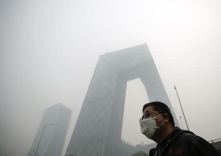 A man wearing a mask walks on a street during a hazy day in Beijing October 10, 2014. REUTERS/Kim Kyung-Hoon