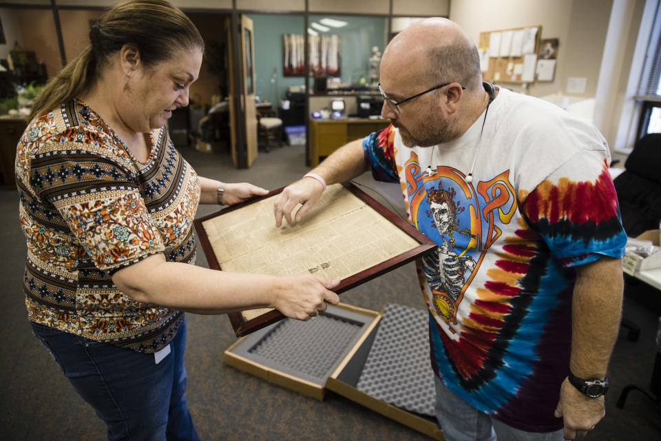 Heather Randall and Mike Storms look over a Dec. 28, 1774 Pennsylvania Journal and the Weekly Advertiser at the Goodwill Industries in Bellmawr, N.J., Thursday, Oct. 25, 2018. A quick eye by Goodwill workers in southern New Jersey turned up an original 1774 Philadelphia newspaper with an iconic "Unite or Die" masthead. (AP Photo/Matt Rourke)