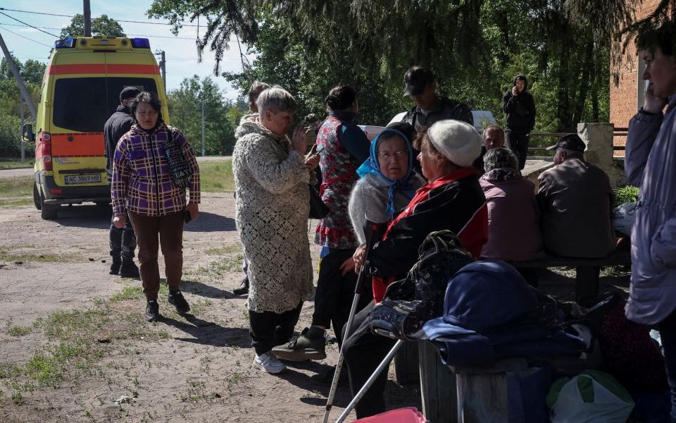 Residents from Vovchansk and nearby villages wait for buses amid an evacuation