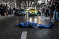 A pro-democracy protester covered in blue paint lies on a road during a protest in Udom Suk, suburbs of Bangkok, Thailand, Saturday, Oct. 17, 2020. The authorities in Bangkok shut down mass transit systems and set up roadblocks Saturday as Thailand’s capital faced a fourth straight day of determined anti-government protests. (AP Photo/Gemunu Amarasinghe)