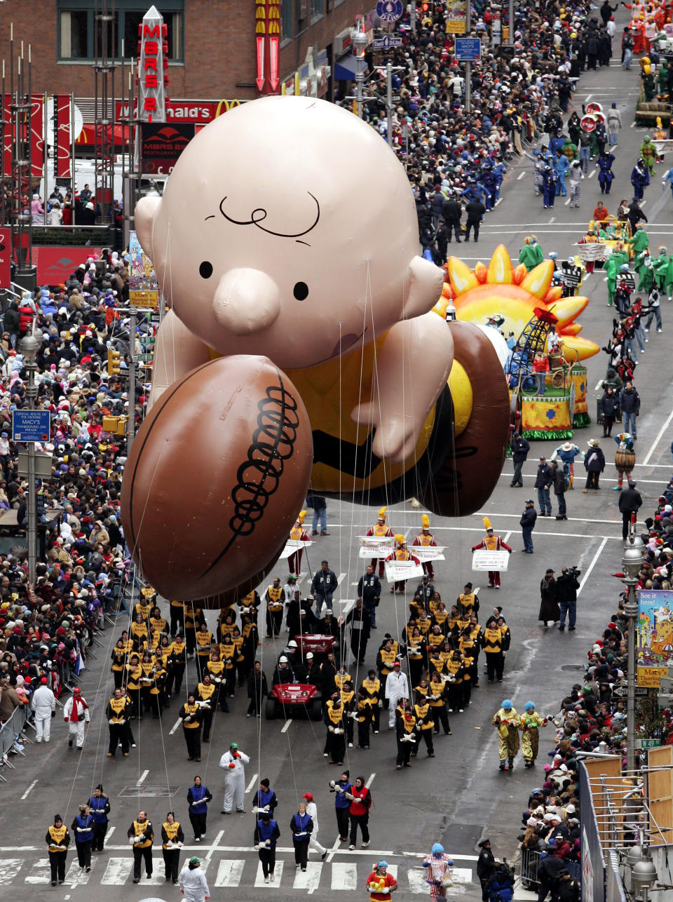 FILE - This Nov. 24, 2005 file photo shows a balloon of Peanuts character Charlie Brown chasing a football down Broadway during the Macy's Thanksgiving Day parade in New York. The parade has to be a crowd-pleaser for a multigenerational crowd. More than 3 million people typically attend the event that also unfolds in front of a TV audience of 50 million. This year's parade will feature balloons include Papa Smurf and the Elf on a Shelf, while Buzz Lightyear, Sailor Mickey Mouse and the Pillsbury Doughboy keep their place in the lineup. A new version of Hello Kitty is also to be included. (AP Photo/Jeff Christensen, file)