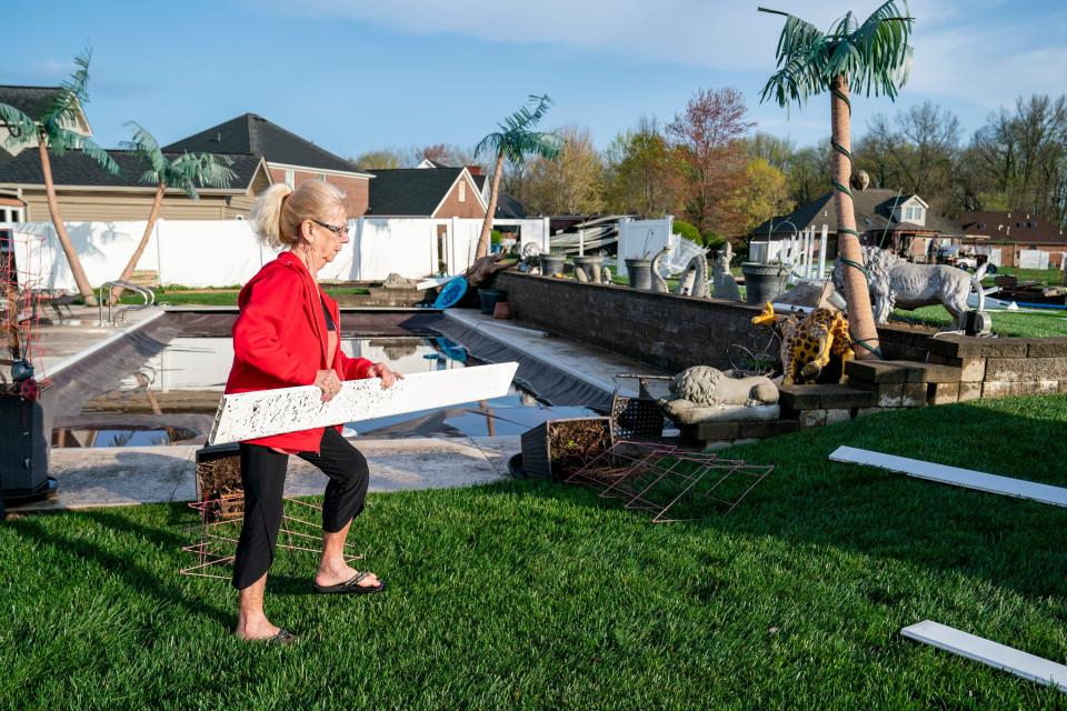 Southern Indiana resident Lois Schmitt picks up a piece of fence in her yard after strong storm came through causing damage around her home Tuesday morning, April 2, 2024.