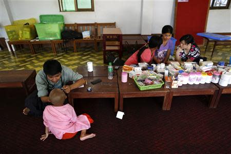 Doctor Ye Thiha Htwe (L) looks at a Buddhist novice nun in the Healthy Farm charity clinic at a monastery outside Yangon November 2, 2013. REUTERS/Soe Zeya Tun