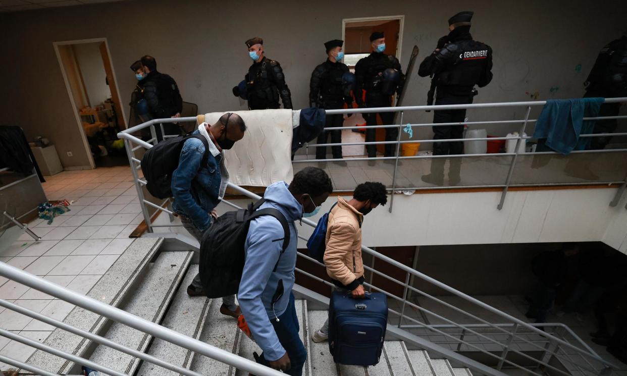 <span>French gendarmes stand by as people leave the squat in an abandoned bus company headquarters. </span><span>Photograph: Emmanuel Dunand/AFP/Getty Images</span>