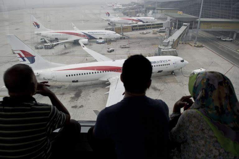 Passengers watch Malaysia Airlines planes on the tarmac at Kuala Lumpur International Airport in Sepang on March 13, 2014