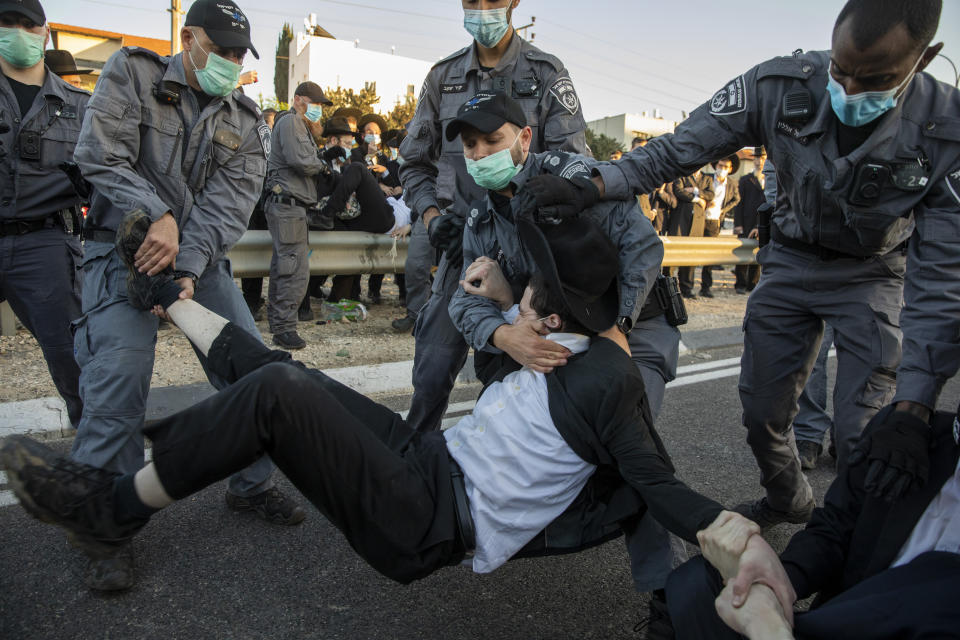 FILE - Israeli police try to clear ultra-Orthodox Jews blocking a highway during a protest against the detention of a member of their community who refuses to do military service in Bnei Brak, Israel, Sunday, Dec. 27, 2020. With ultra-Orthodox parties now wielding unprecedented power and playing a key role in a contentious plan to overhaul the legal system, they are aggravating concerns among secular Israelis that the character and future of their country is under threat. (AP Photo/Ariel Schalit, File)