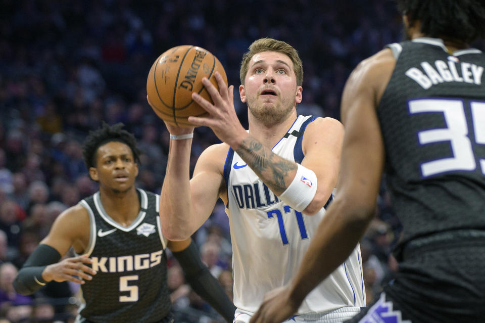 Dallas Mavericks forward Luka Doncic (77) drives to the basket past Sacramento Kings guard De'Aaron Fox (5) and forward Marvin Bagley III (35) during the first quarter of an NBA basketball game in Sacramento, Calif., Wednesday, Jan. 15, 2020. (AP Photo/Randall Benton)