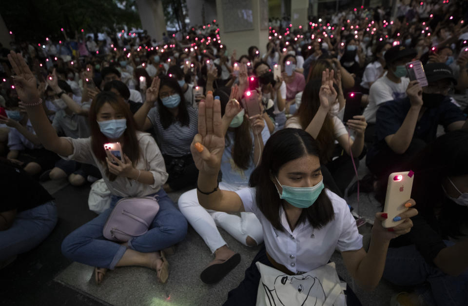 Pro-democracy students raise a three-finger symbol of resistance salute and hold mobile phones with flashlights switched on†during a protest at Chulalongkorn University in Bangkok, Thailand, Friday, Aug, 14, 2020. Student activists at Thailand's most prestigious university defied a ban by college administrators to stage an anti-government rally Friday, even as a prominent protest leader was arrested elsewhere for his involvement in a previous demonstration. (AP Photo/Sakchai Lalit)