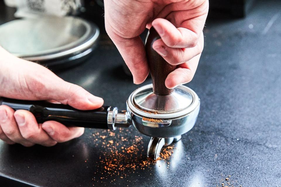 tamping down espresso on countertop