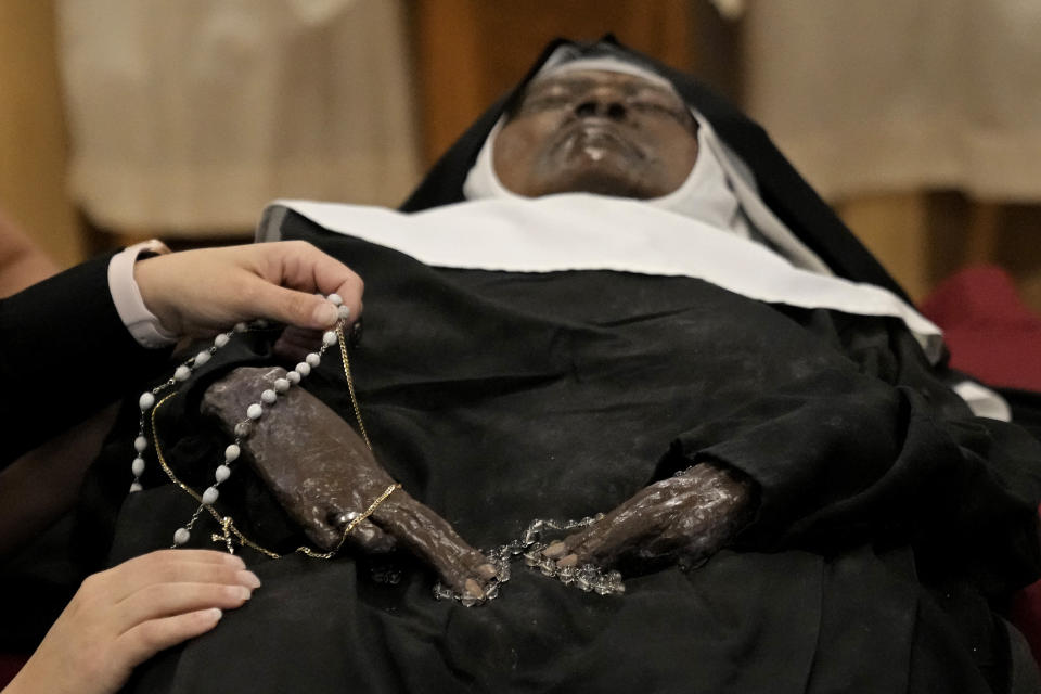 People pray over the body of Sister Wilhelmina Lancaster at the Benedictines of Mary, Queen of Apostles abbey Sunday, May 28, 2023, near Gower, Mo. Hundreds of people visited the small town in Missouri this week to see the nun's body that has barely decomposed since 2019 — some are saying it's a sign of holiness in Catholicism, while others are saying the lack of decomposition may not be as rare as people think. (AP Photo/Charlie Riedel)