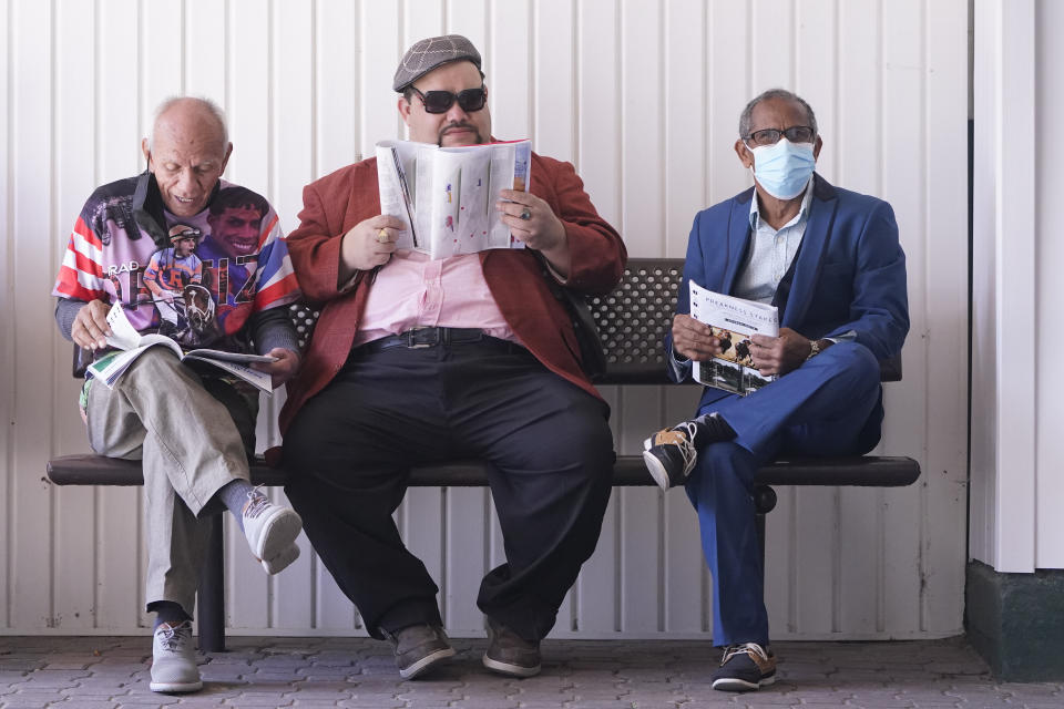 Men look at racing programs before the 147th running of the Kentucky Derby at Churchill Downs, Saturday, May 1, 2021, in Louisville, Ky. (AP Photo/Michael Conroy)