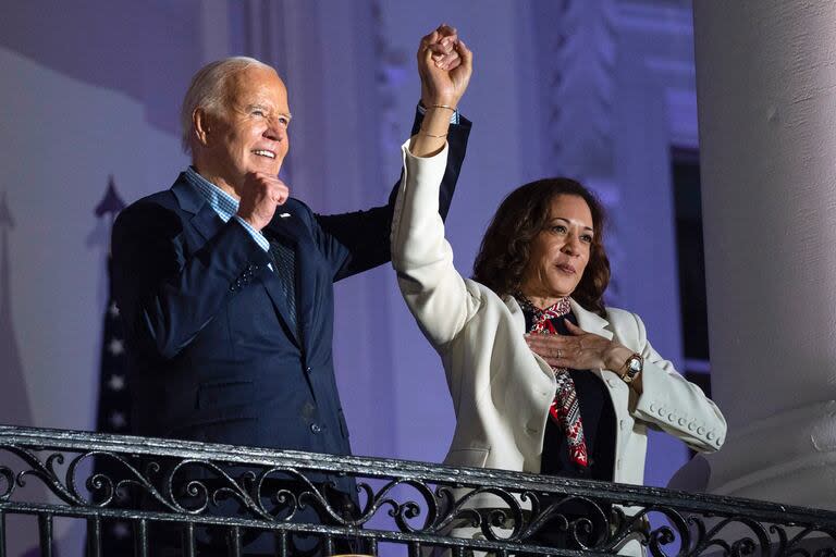 El presidente estadounidense Joe Biden alza la mano de la vicepresidenta Kamala Harris tras observar los fuegos artificiales lanzados por el Día de la Independencia desde el balcón de la Casa Blanca, el jueves 4 de julio de 2024, en Washington (AP Foto/Evan Vucci)