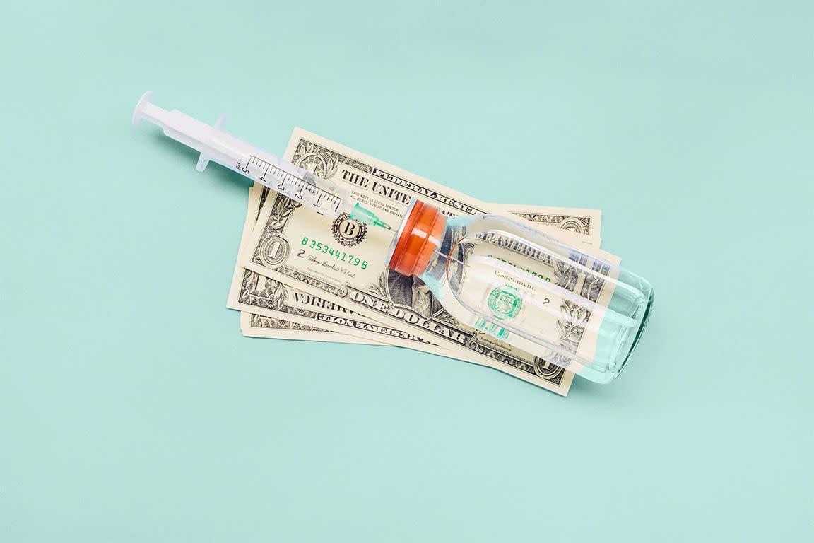still life of a syringe, ampoule and american dollar banknotes on blue background