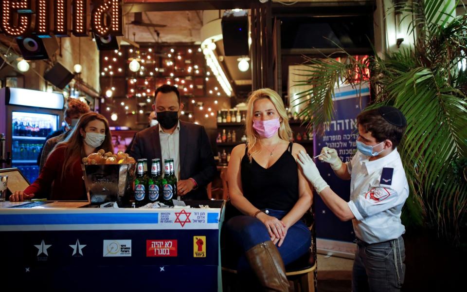 A woman receives a vaccination against the coronavirus disease (COVID-19) as part of a Tel Aviv municipality initiative offering a free drink at a bar to residents getting the shot - CORINNA KERN/REUTERS