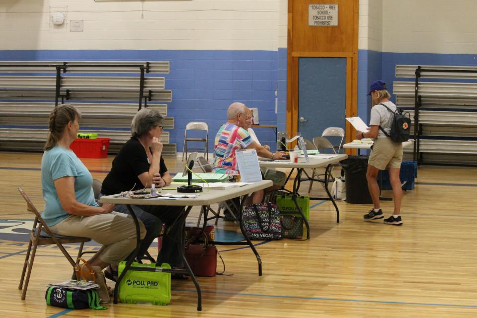 Poll workers help voters during the CD1 primary at Middletown High School