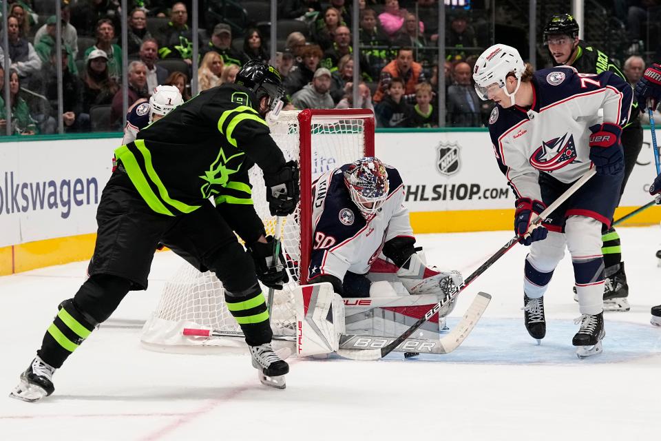 Dallas Stars center Matt Duchene, left, takes a shot as Columbus Blue Jackets' Elvis Merzlikins (90) and Damon Severson defend the net in the first period of an NHL hockey game, Monday, Oct. 30, 2023, in Dallas. (AP Photo/Tony Gutierrez)