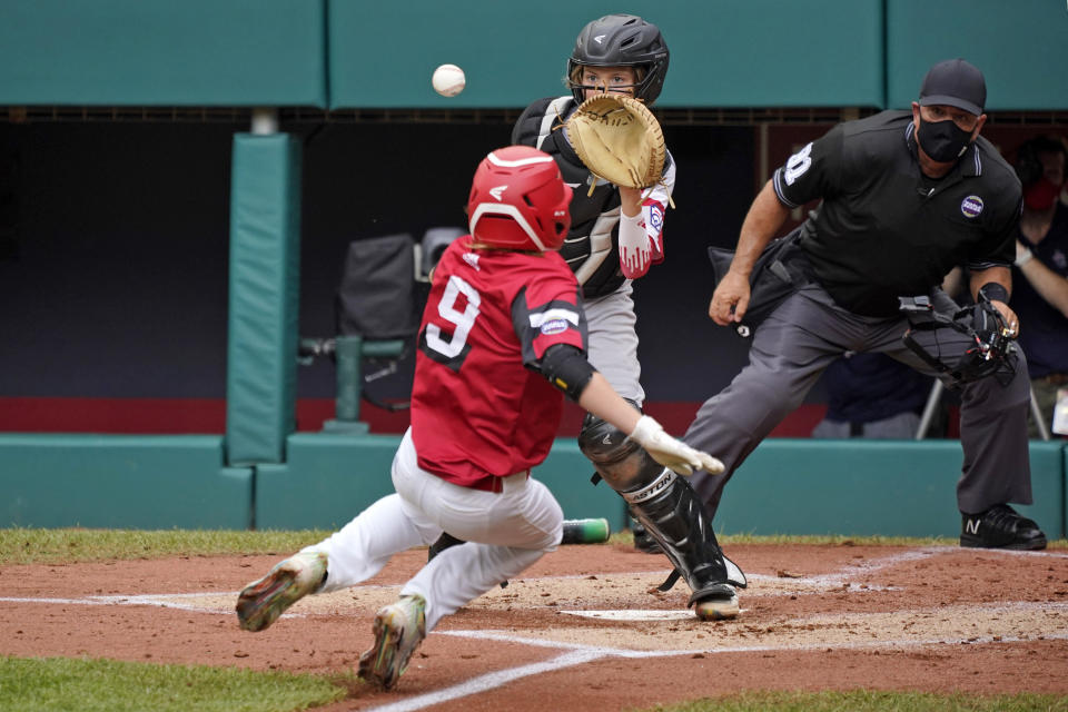 Sioux Falls, S.D. catcher Easton Riley, center, waits for the throw before making the tag and getting the out at home on Hamilton, Ohio's Levi Smith (9) who was attempting to score on a fielder's choice by JJ Vogel during the second inning of a baseball game at the Little League World Series in South Williamsport, Pa., Saturday, Aug. 28, 2021. (AP Photo/Gene J. Puskar)