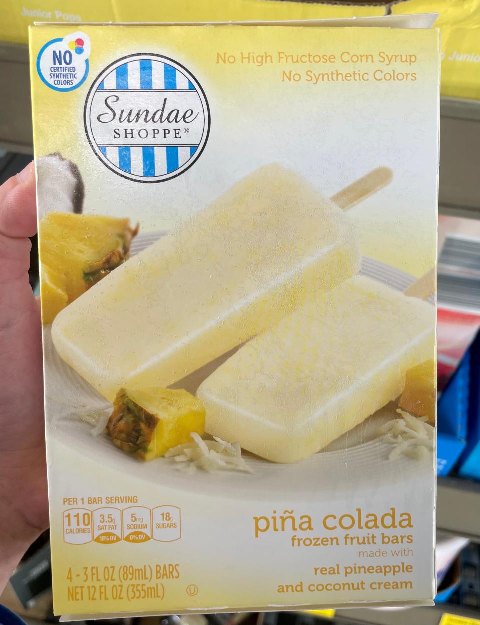 Handing holding a yellow box of pina colada pops